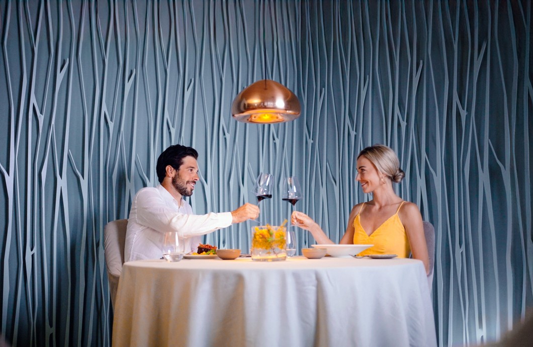 Ein nettes Paar, das am Tisch im Artifex-Restaurant sitzt und mit einem Glas Wein anstößt.
