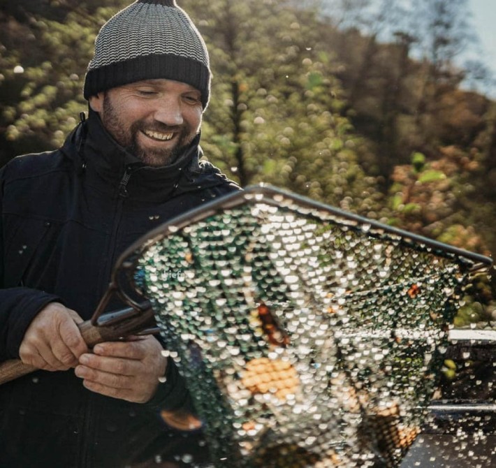 Fischer fischt einen Fisch aus dem Wasser